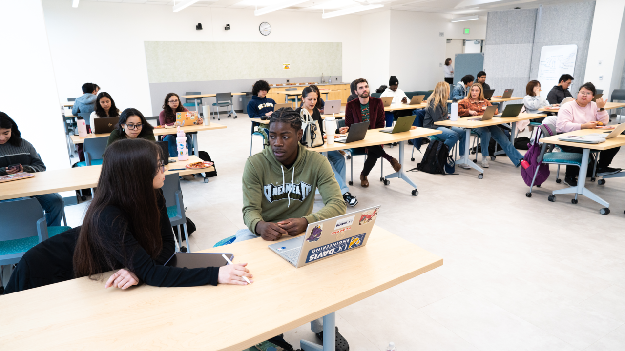 Small groups of students gathered around multiple tables 