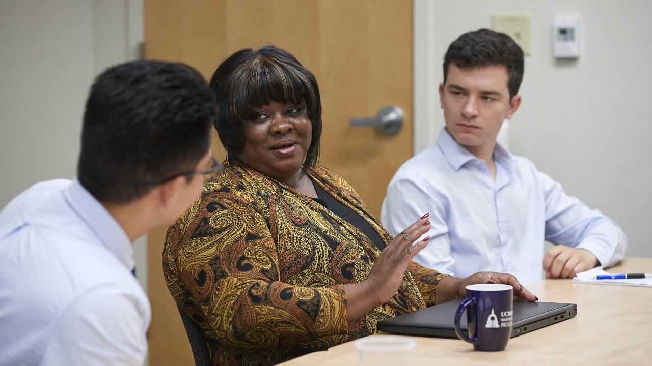 Cheryl Purifoy meets with two students. 