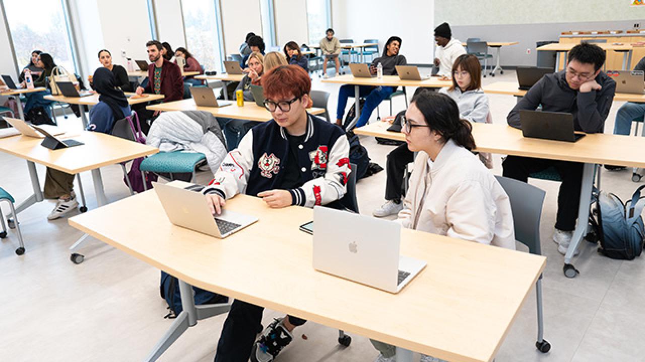 Several students working together at tables in the Writing Center classroom