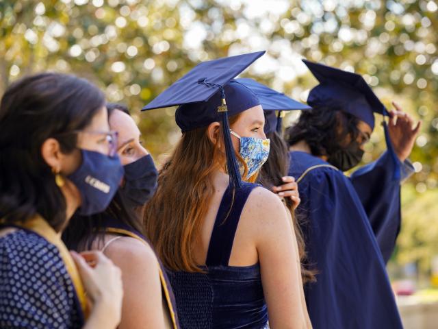 Students outdoors wearing grad caps and masks