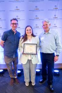 a student and two faculty mentors posing with a certificate.