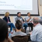 A panel of four speakers addressing a crowd