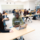 Small groups of students gathered around multiple tables 