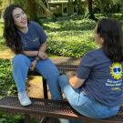 two students sitting in the courtyard on a picnic table. Both are wearing Summer Sessions t-shirts.