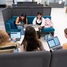 Looking down on a group of students seated around a table who are all working on laptops.