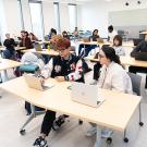 Several students working together at tables in the Writing Center classroom